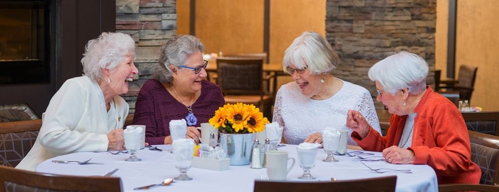 senior women around dinner table laughing