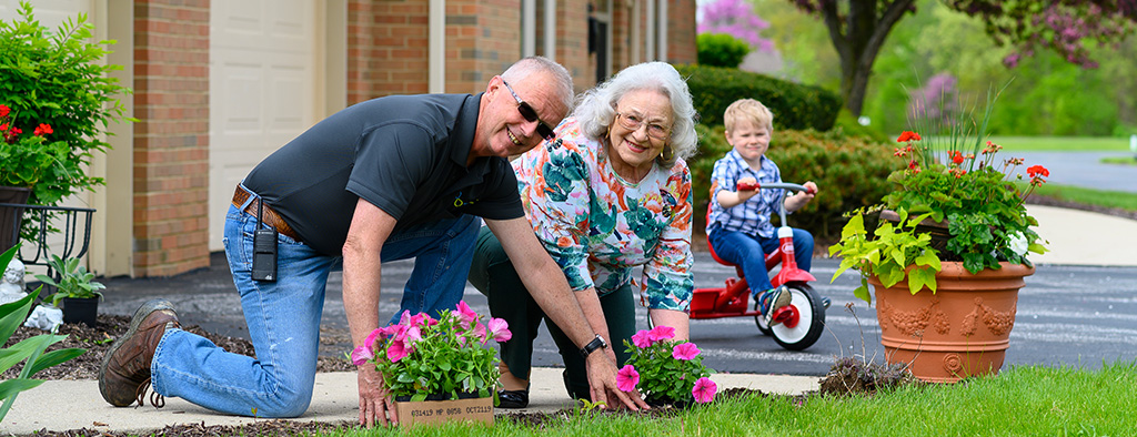 otterbein seniorlife residents planting flowers with grandchild riding bike