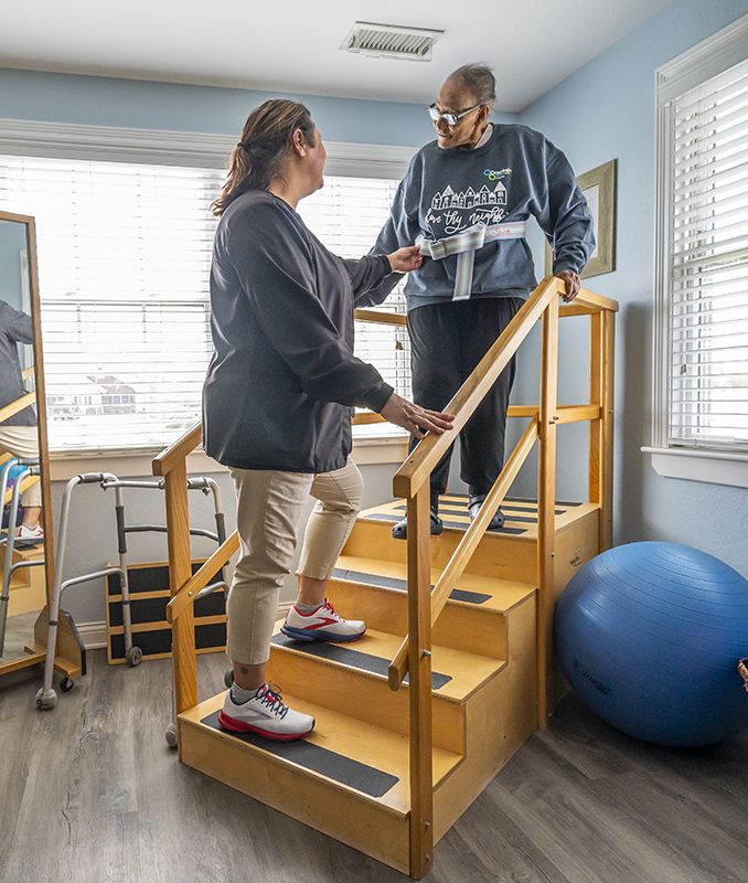 physical therapist assisting resident with stairs