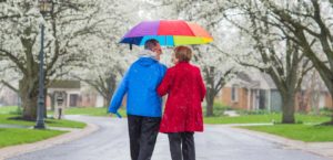 Couple walking in the rain while holding a colorful umbrella
