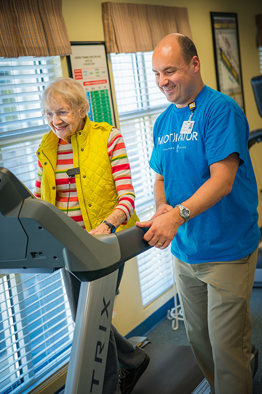 physical therapist assisting resident on treadmill