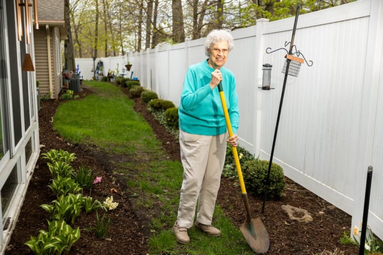 a woman outside holding a shovel next to her landscaping