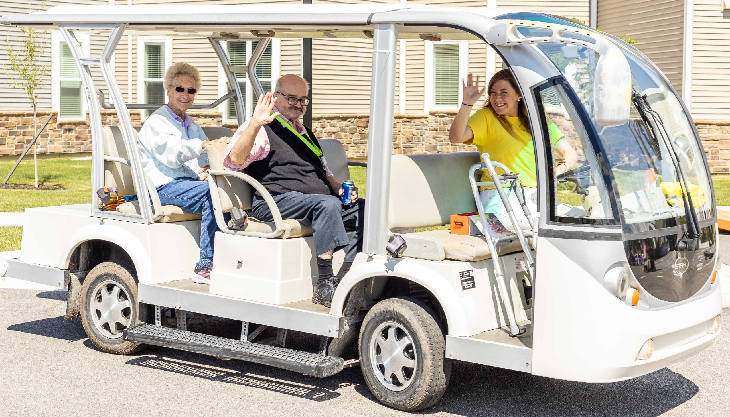 two Otterbein residents and a staff member driving a transportation cart