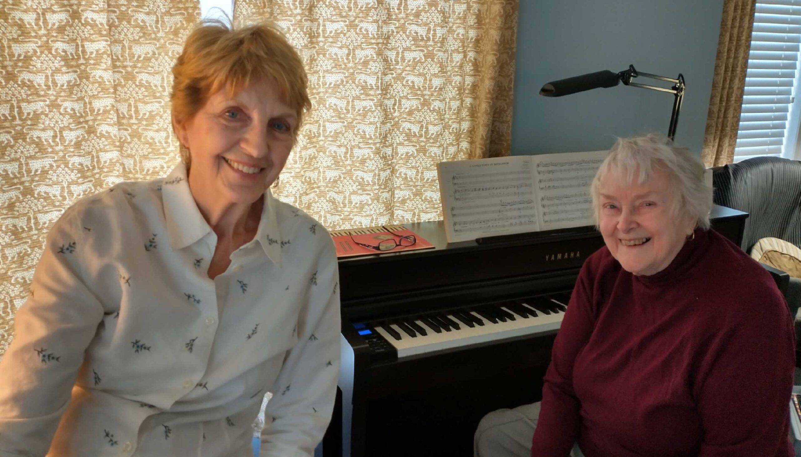 two women smiling next to a piano