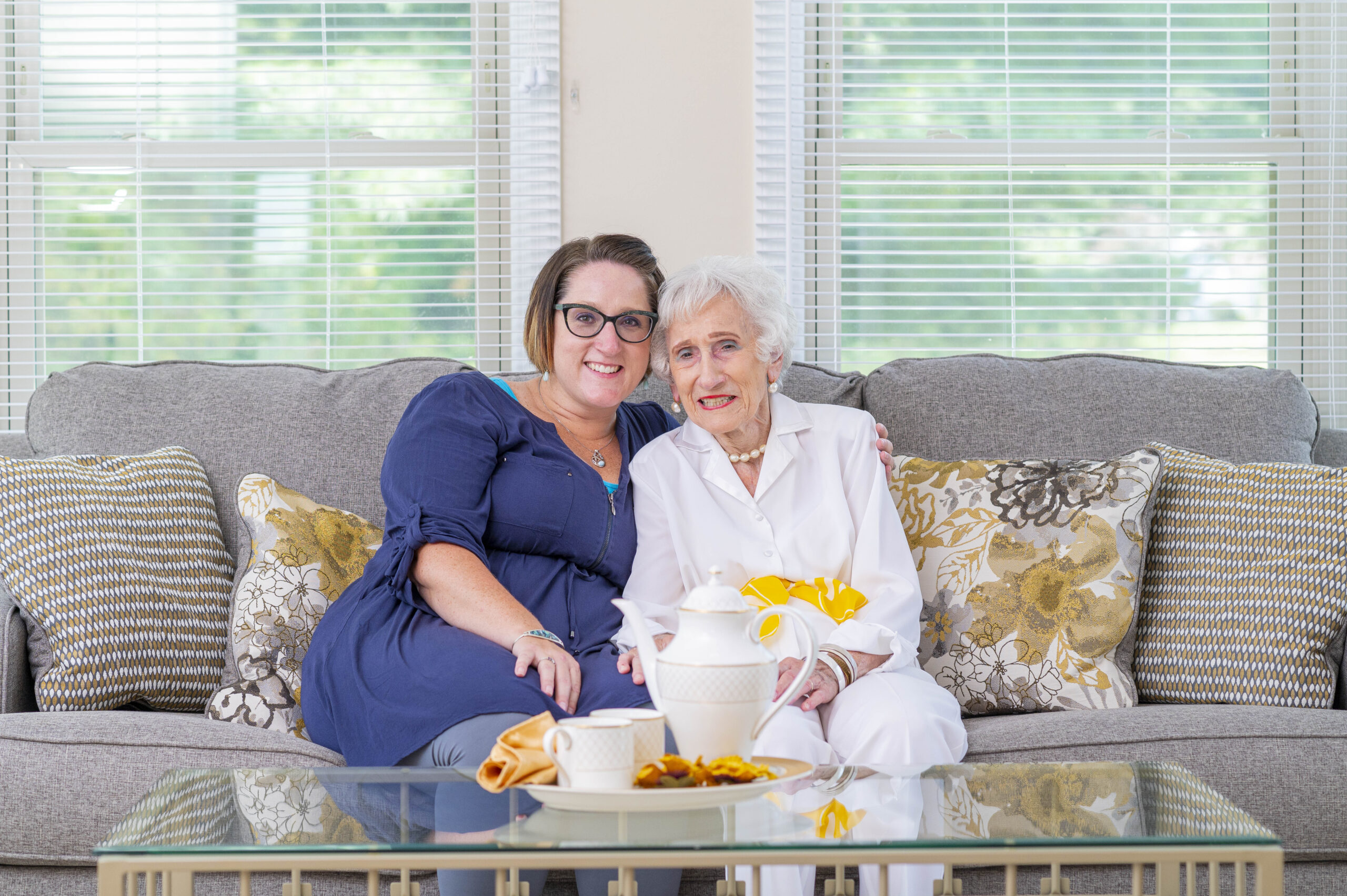 Two women sitting on a couch smiling