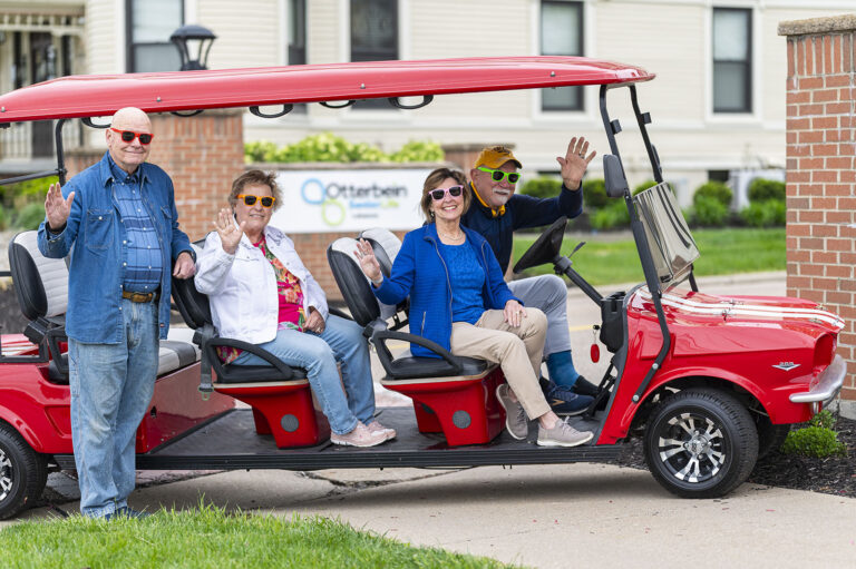 Otterbein Lebanon residents smiling and waving while sitting on a golf cart