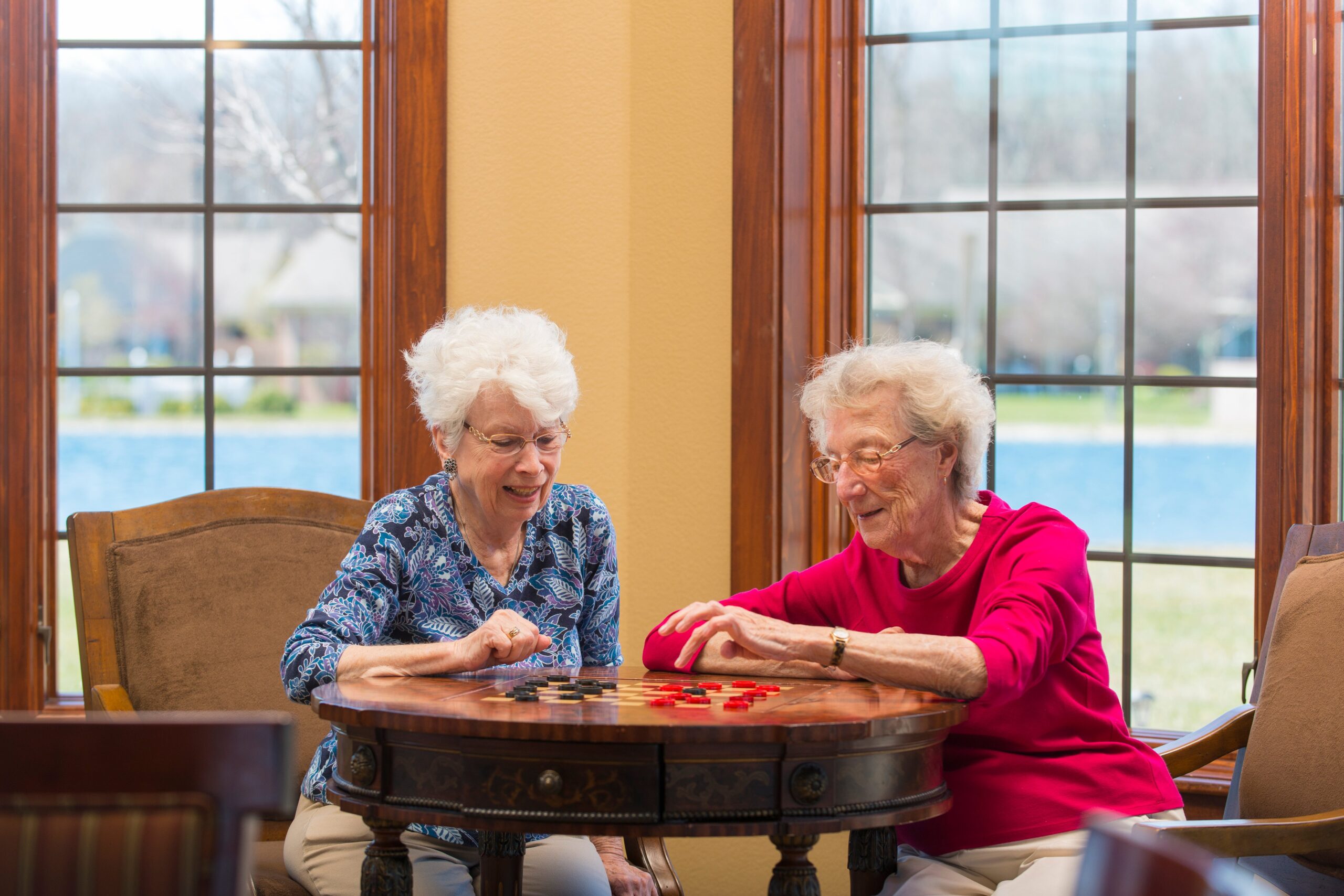 Two senior women in assisted living playing checkers