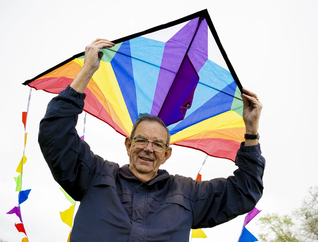 Otterbein resident holds a brightly colored kite above him
