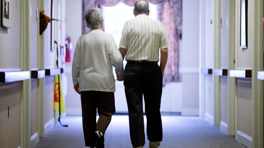 Otterbein resident couple holds hands and walk down a hallway