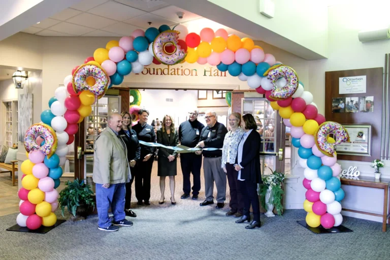 Otterbein team and residents celebrating dedication with ribbon cutting and large archway of balloons