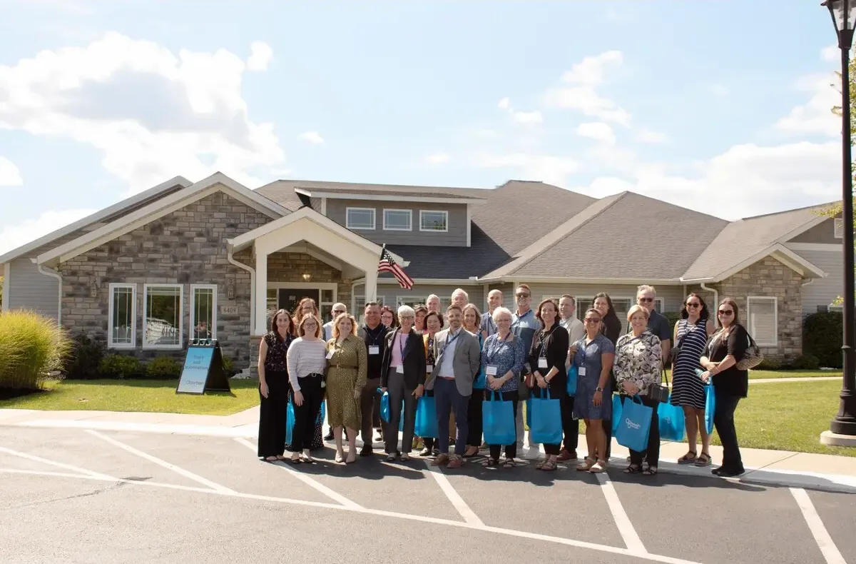 Otterbein team standing together in front of an Otterbein small house