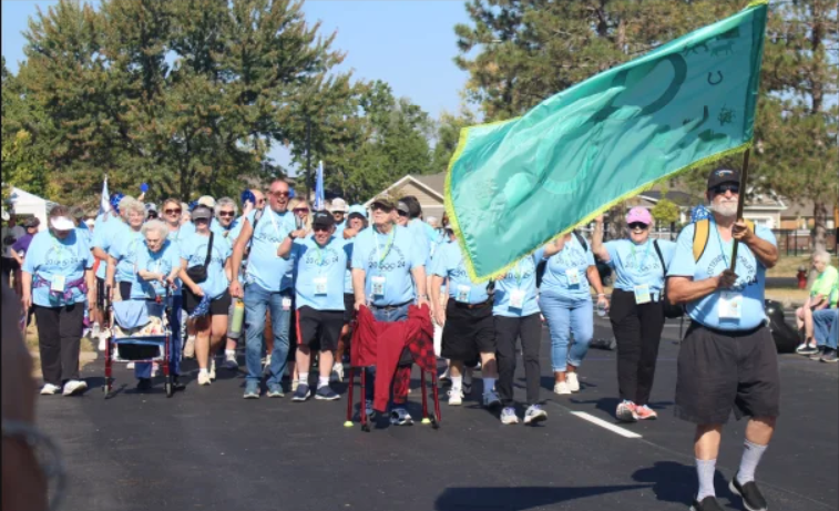 Otterbein Olympics ceremony with resident carrying large flag and residents walking behind him