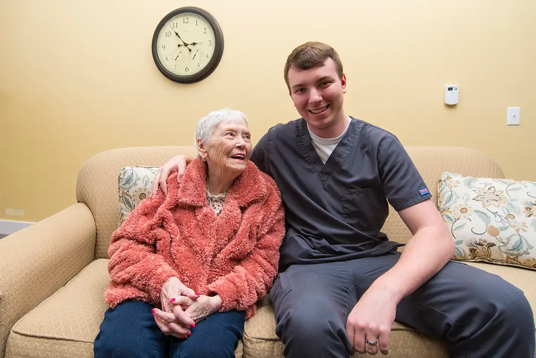Otterbein small house elder assistant and elder sit together on the sofa