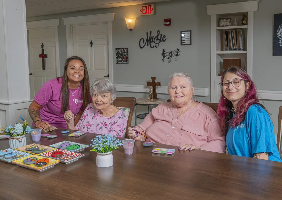 Otterbein small house elders and elder assistants paint rocks together at the dining table