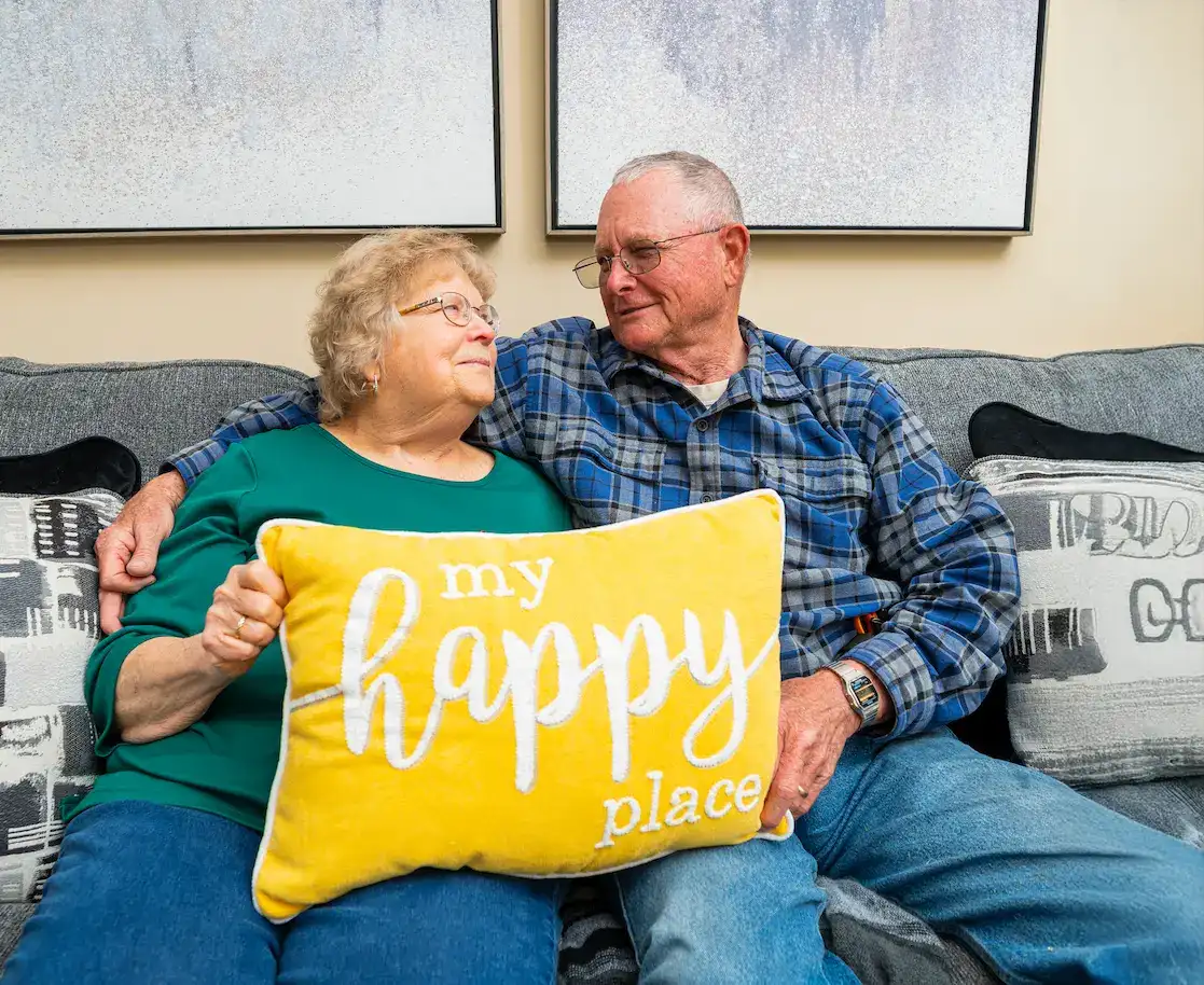 Otterbein St. Marys resident couple holding My Happy Place pillow while seated on a couch