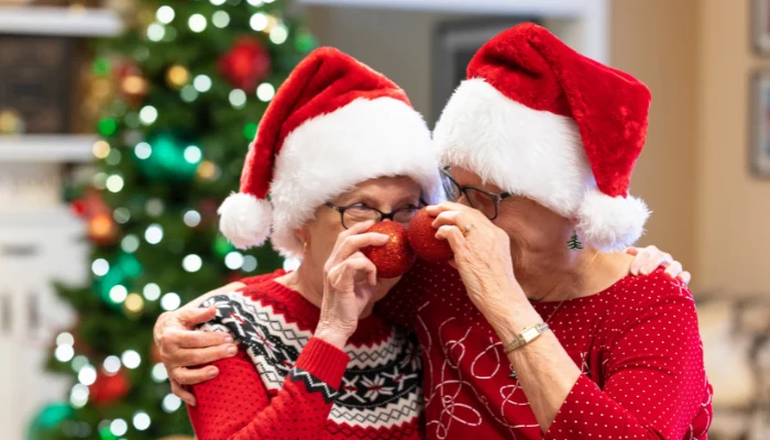 Otterbein Residents Celebrating the Holidays by wearing Santa hats and holding red ornaments up to their noses