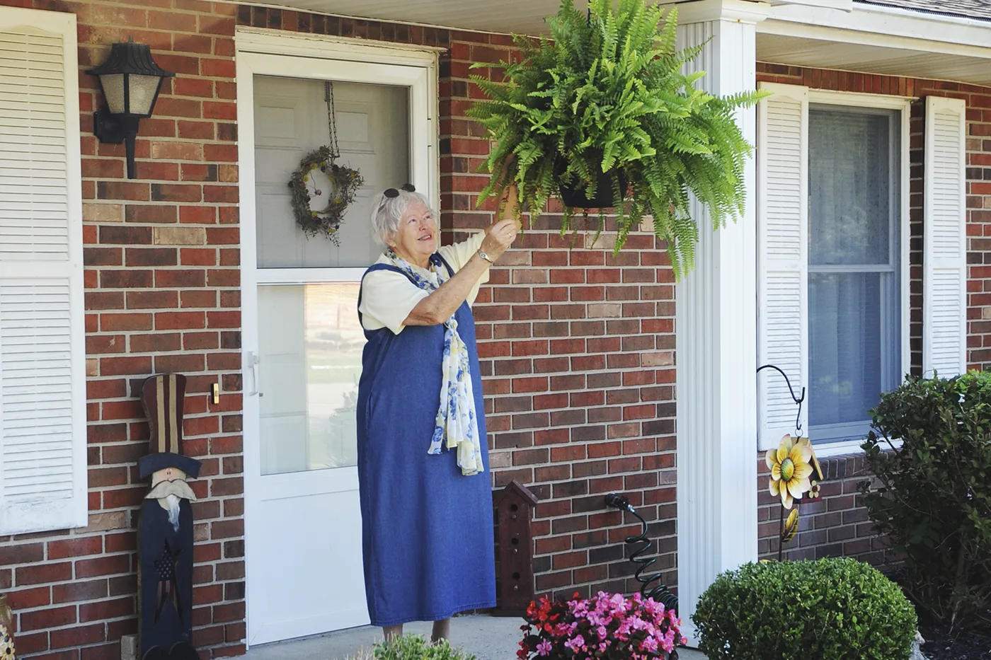 Female resident tending to hanging planter outside an independent living home at Otterbein Green Hills