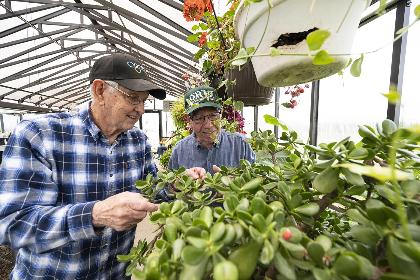 Two male residents tend to plants in the community's greenhouse