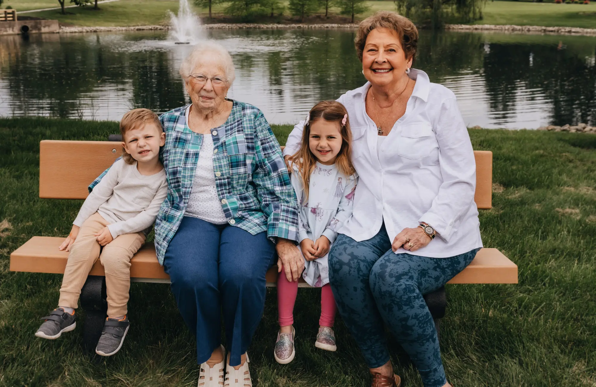 Resident and family sitting together outside on a bench by a pond at Otterbein SeniorLife