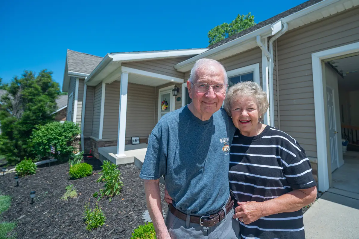 Independent Living Couple standing in front of their home